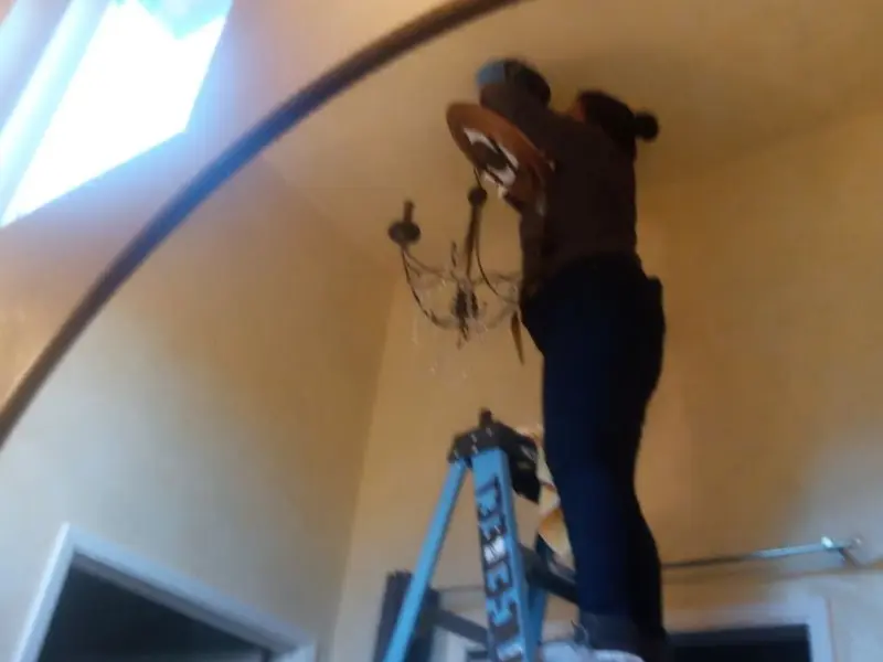 Electrician installing a chandelier in a Weston residence